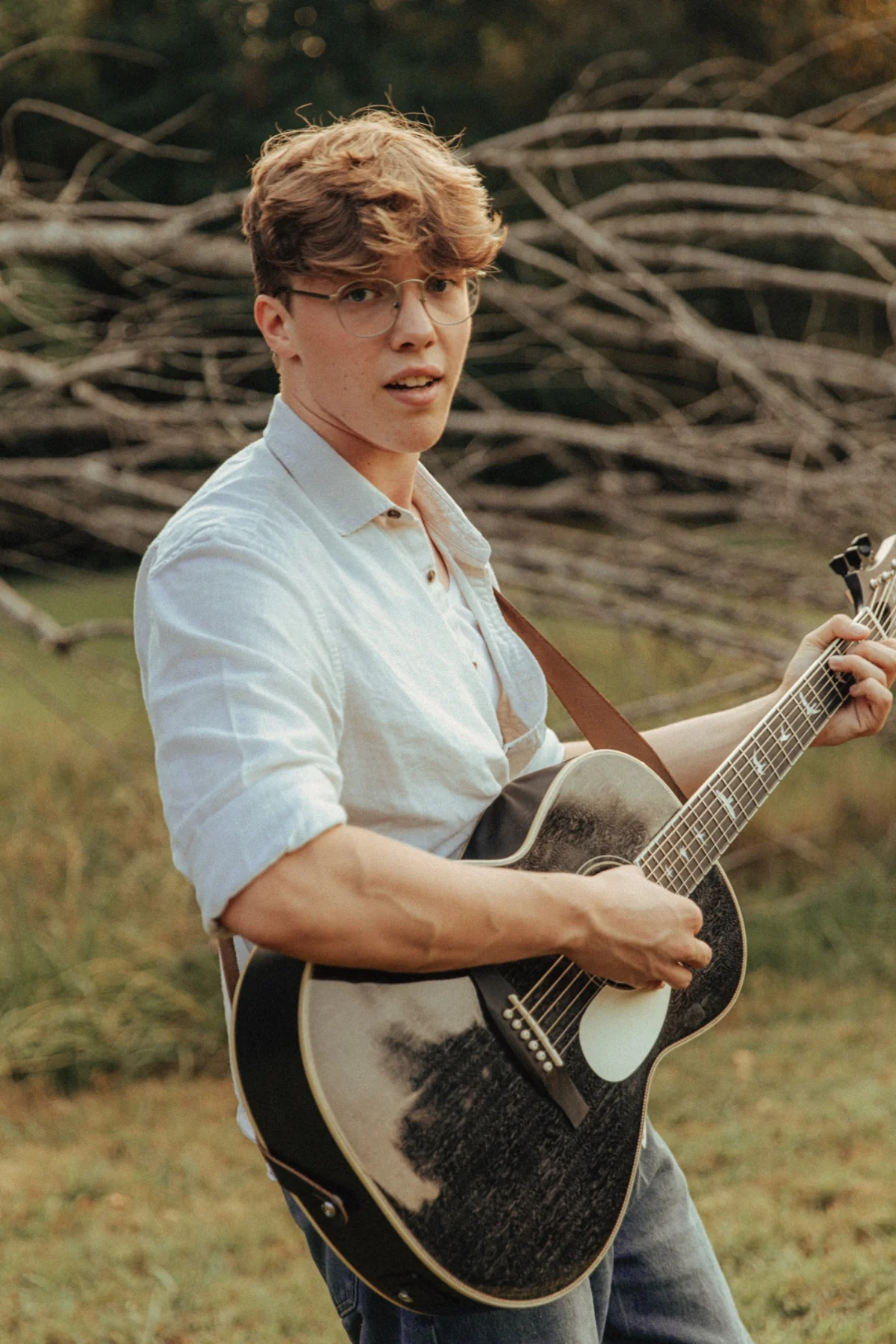 Kadin Alexander holding an acoustic guitar in a warm outdoor portrait