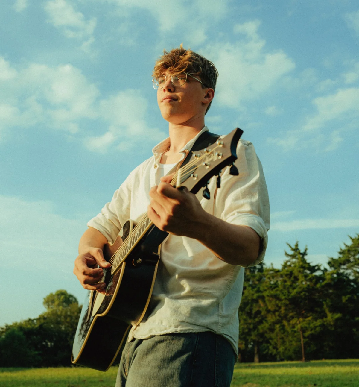 Kadin playing guitar beneath a blue sky
